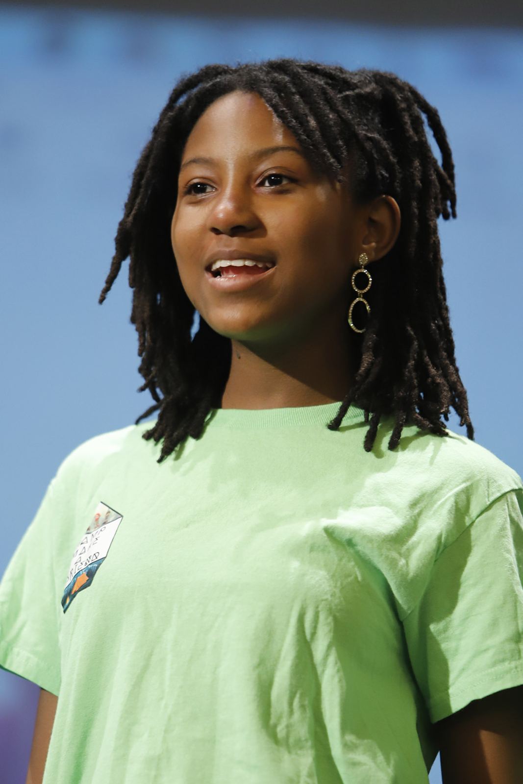 A student in a green T-shirt sings on stage in Camp Galileo, Spring 2026