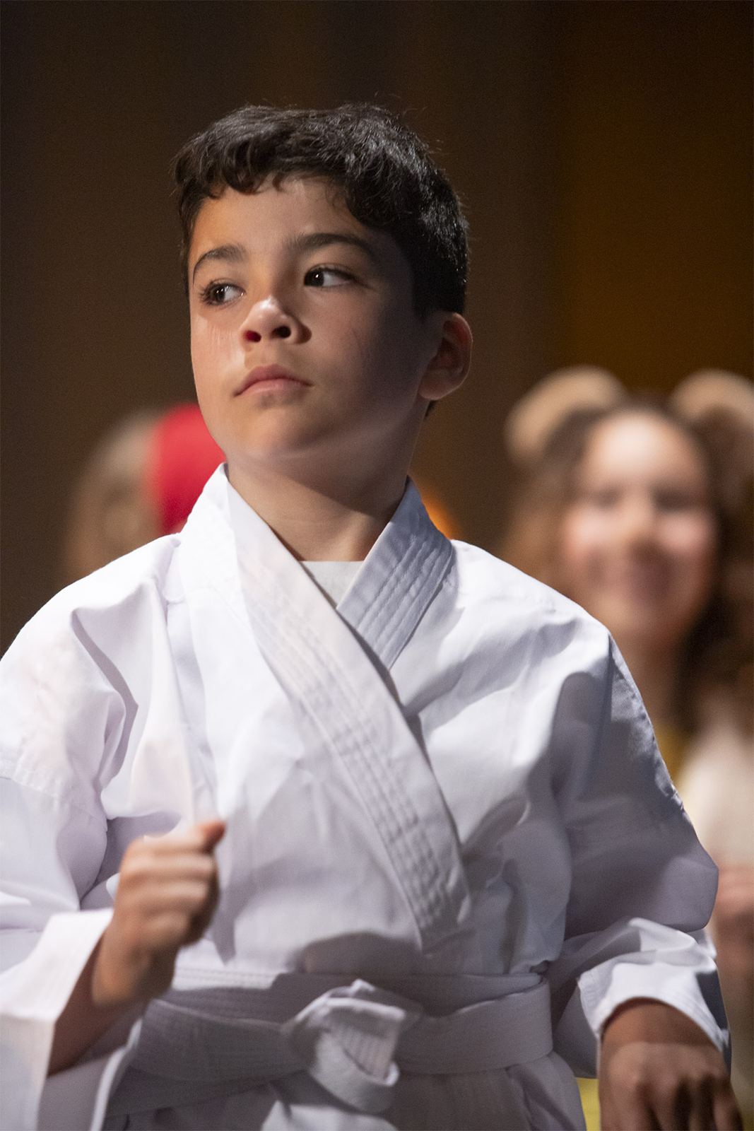 A student in a white martial arts uniform performs in The Great Cake-tastrophy, Spring 2026