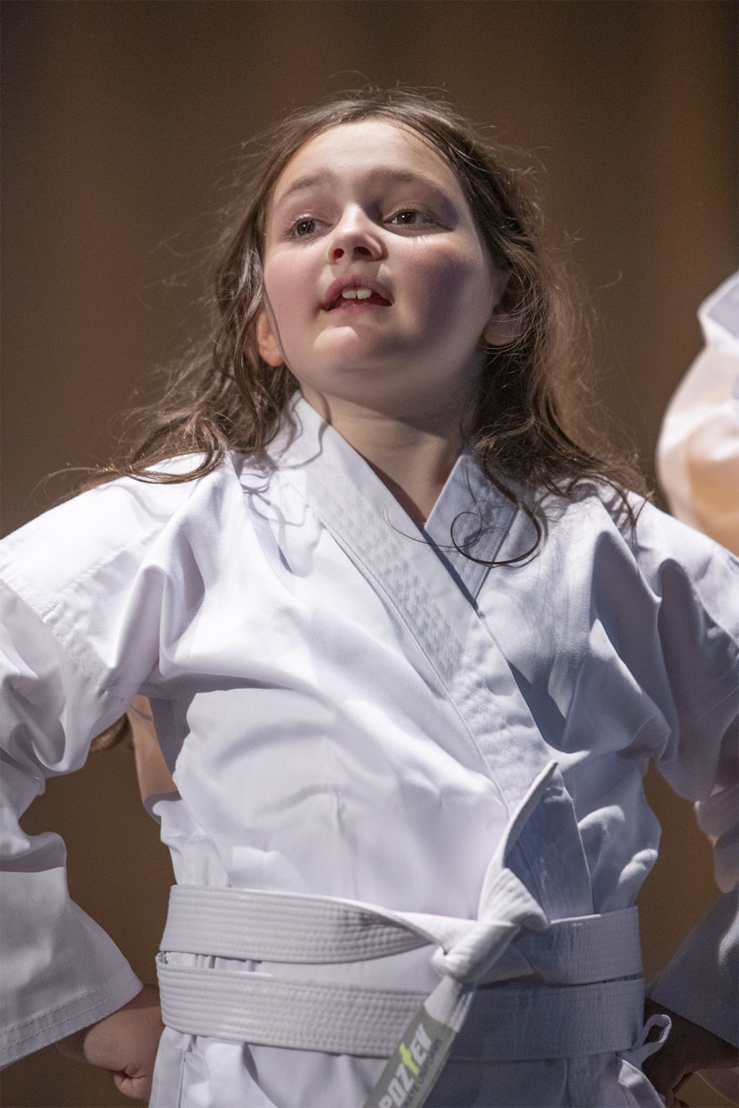 A student in a white martial arts uniform strikes a pose in The Great Cake-tastrophy, Spring 2026