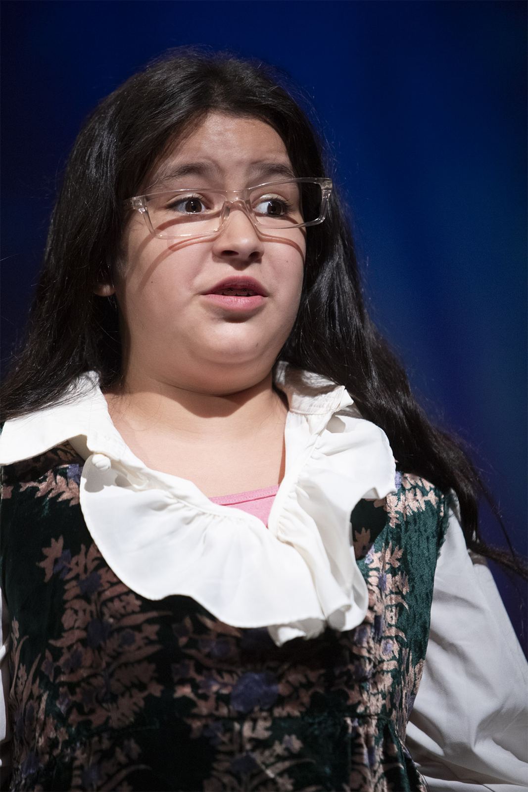 A student in glasses and a ruffled collar sings in The Legend of Tart, Spring 2026
