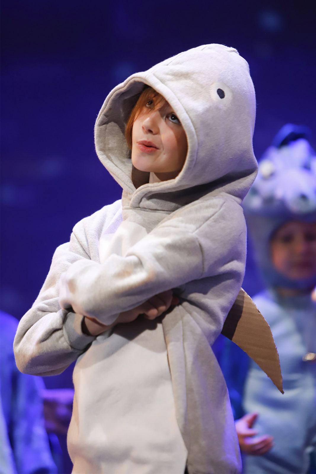 A young performer in a gray fish hoodie crosses their arms in Ocean’s Got Talent, Spring 2026